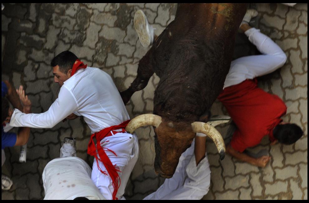Fotografía de Eloy Alonso para Nthephoto. Runners fall in the path of an El Pilar fighting bull at the entrance to the bullring during the seventh running of the bulls at the San Fermin festival in Pamplona July 13, 2011. There were no serious injuries during the run that lasted two minutes and 11 seconds, according to local news sources. © Eloy Alonso (SPAIN)