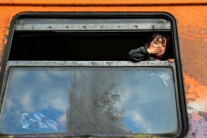 Fotografía de Czuko Williams para Nthephoto. Una niña siria lanza un beso desde el sucio vagón de tren que une la frontera de Macedonia con la de Serbia en la Ruta de los Balcanes.